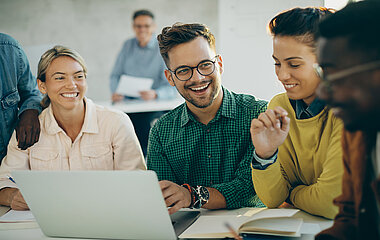 Study Talk Ein glücklicher College-Student und seine Freunde benutzen einen Laptop und lernen gemeinsam im Klassenzimmer.